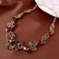 Dettaglio della collana vintage dorata con pietre rosse su tessuto di raso marrone - Collana Oro