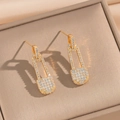 Detailed view of gold safety pin earrings with pave cubic zirconia in a beige box - Gold Safety Pin Stud Earrings (835)
