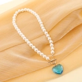 Dettaglio collana di perle con gemma a cuore verde acqua e chiusura a T dorata - Blu Lago