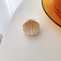 Detalle de una pinza para el cabello de acetato con forma de concha y rayas doradas - Blanco concha