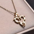 Detail of 18k gold plated heart pendant necklace with tribal flame design on beige cushion - Necklace / Gold