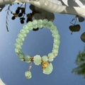 Light green beaded pearl bracelet with gold charms reflected on a mirror - S048-donglin Jade Beaded Bracelet With Money Bag Design #sz341