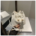 Detail of white woven bucket bag featuring gold sphere accents and thick rope drawstring - White Strawberry
