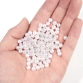 Hand-held shot of 4mm-6mm white round faux pearls showing realistic size and gloss - 5mm (300pcs/Pack) / No Hole Pure White