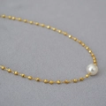 Elegante goldene Perlenkette mit einem weißen Perlenanhänger auf grauem Hintergrund - Vergoldet + Weiße Kunstperle