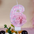 Detailed macro shot of pink glitter number 6 birthday candle with a bow decoration - Number 6