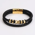 Detalle de pulsera de cuero trenzado negro con cierre magnético dorado y adornos de cilindro - Dorado