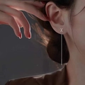S925 sterling silver letter X tassel drop earrings worn by a model in soft lighting - Letter X