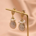 Baroque pearl earrings in gold finish hanging on a stand with silk background - Water Drop Pearl Style