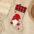 Beige burlap Christmas stocking with gnome applique and red plaid cuff on wood floor - Heart Style