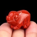Miniature hand-carved red jasper pig figurine held between fingers for size reference - Red Jasper