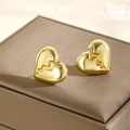 Dettaglio macro di orecchini a cuore dorato con venature a fulmine su scatola in pelle - Cuore Spezzato Oro