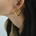 Polished gold U-shaped hollow hoop earrings with geometric twisted design worn by model - Gold