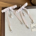 Detail van roze polkadot strik oorbellen met parels en kristallen in een houten dienblad - Roze