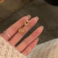Boucles d'oreilles nœuds dorés irréguliers au fini métallique poli sur les doigts - Boucle d'oreille / Doré