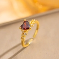 Detail of heart-shaped ruby ring with side diamonds on gold band and silk background - Red Heart Style / Gold with Red Zirconia