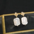 Baroque pearl earrings with golden wavy metal tops shown on a black background - Square Fold Stud White Square Baroque
