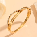 Macro detail of gold plated geometric bangle with sparkling white zircon stones - Gold Cross Multi-Layer Style (M812)