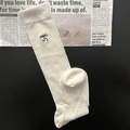 Détail de la maille blanche avec broderie nœud noir sur un fond de journal de mode - Beige