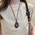 Detailed view of dark brown oval wood pendant with minimalist wax rope on linen shirt - 22# Necklace - Coffee