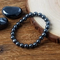 Bracelet en perles d'hématite noire polie au design zen minimaliste sur fond de bois - Hématite