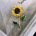 Macro detail of a sunflower brooch with yellow enamel petals on a marble surface - Sun Flower Style (X0189)