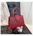 Detail of burgundy PU leather handbag with crocodile pattern texture on a black chair - Red