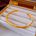 Dettaglio del bracciale aperto in oro vintage con incisioni floreali di loto e finitura opaca - Fiore Cavo Dorato (WB1581)