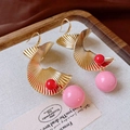 Detail of gold spiral earrings with pink and red beads on a wooden display stand - Gold Spiral Ear Hook