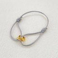 Detailed macro of grey woven cord bracelet featuring triple golden interlocking rings - All Gold Rings And Gray Cord