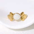Elegante anello in acciaio dorato con centro in smalto bianco e dettagli floreali - Regolabile / Bianco Perlato