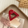 Dettaglio di una pinza per capelli rossa in acetato su un vassoio dorato elegante - Triangolo / Rosso