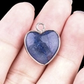 Silver-plated heart pendant with dark blue textured stone inlay held in hand - Blue Aventurine Silver Edging