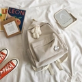 Detail of minimalist cream backpack with plush bear charm and cute rabbit badge - Off-white with Pins and Bear Pendant