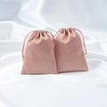 Pink satin drawstring jewelry pouches with a smooth matte finish on white silk background - Pink