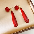 Detalle de pendientes de perlas rojas con broches dorados sobre satén champán - Estilo Gota de Agua Rojo Vermellón / Rojo