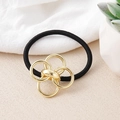 Detail of black elastic hair tie with gold interlocking rings on a textured surface - Gold Five Interlocking Rings