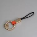 Portachiavi in pelle arancione con anelli dorati e cordino intrecciato nero chic - Rosso + Oro