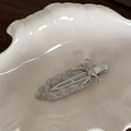 Macro view of a silver sword-shaped metal hair clip with a bow and rhinestones in a shell dish - Rhinestone Silver Bow