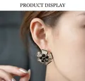 Detailed macro shot of a crystal flower earring worn on ear featuring black and white zircon - Black