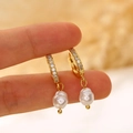 Detailed view of baroque pearl earrings with gold-plated zircon hoops held by hand - Pave Zirconia Hoop Baroque Pearl Drop