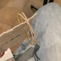 Dettaglio di orecchini a cerchio intrecciati dorati con micro-pave di zirconi - Oro