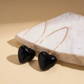 Detalle macro de pendientes de corazón negro vintage con ganchos dorados sobre piedra - Gancho de oreja - Negro