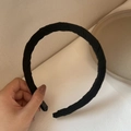 Handheld view of a wide black fabric wrapped headband with a handmade label - Black