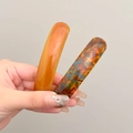 Translucent orange and tortoiseshell spring hair clips held against a solid background - Amber + Blue Brown
