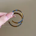 Macro detail of retro amber and blue resin C-shaped hoop earrings held by fingertips - Tortoiseshell Texture Hoop / Coffee Blue (6# Silver Needle)
