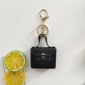 Detail view of mini black PU leather bag keychain with gold clasp and chain on white - Black