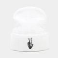Detail of white knit beanie featuring black skull hand gesture embroidery on cuff - White