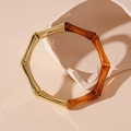 Detalle de pulsera de bambú con metal dorado y resina marrón sobre soporte de piedra - Brazalete de Bambú Color Café