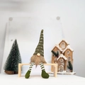 Green polka dot Christmas gnome plush with striped legs sitting on a wooden bench - Green